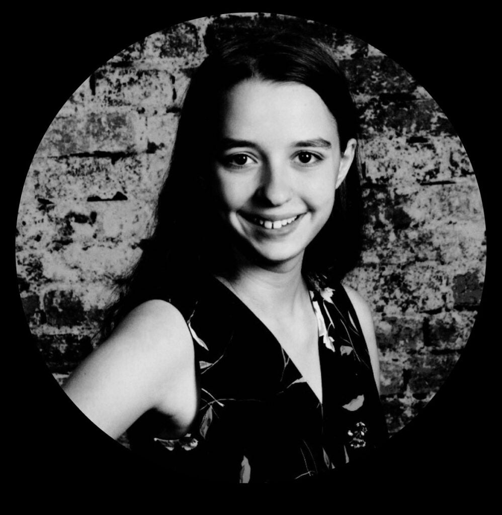 A black and white photo of Beverly Funderburk, smiling, against a brick wall.