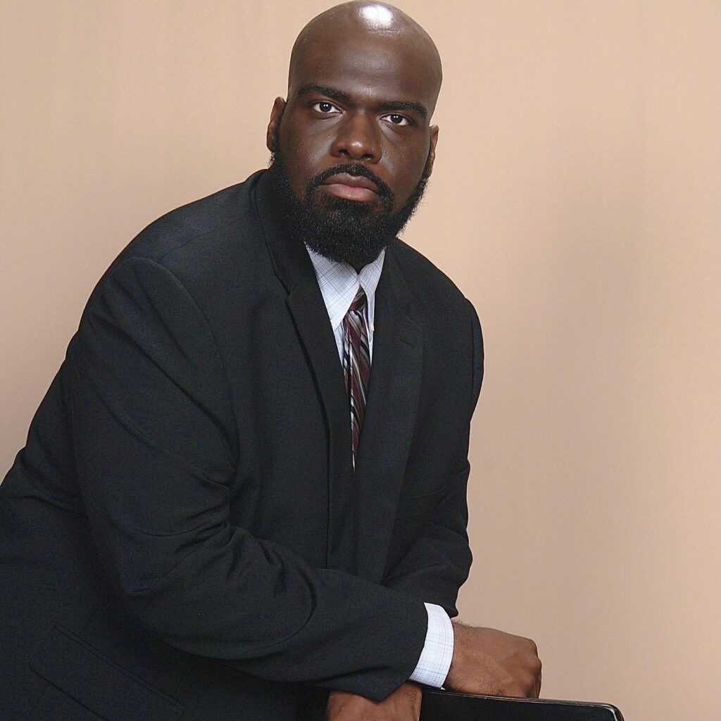A photo of Fredrick Bishop, wearing a suit and looking into the camera.