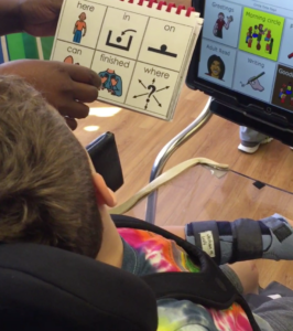 a universal core vocabulary book is held in front of a student in a wheelchair