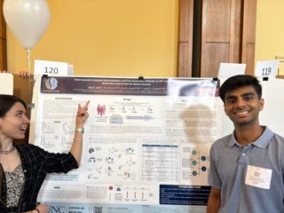 Alice and her mentee Rahul in front of Rahul's poster