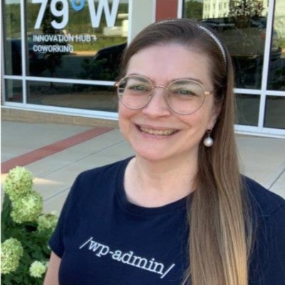 Carolyn Clabo in blue tshirt with words wp admin standing near 79 west coworking office