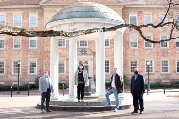 four leaders from grad school standing by old well