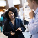 Rising Star program image of diverse woman speaking to a white man at a poster session