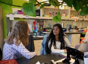 Jill Dowen sits and works with student in Riya in lab