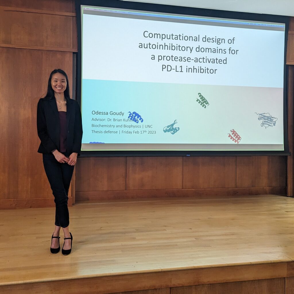 Odessa Goudy standing by presentation stage at PhD Defense in February 2023