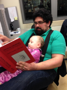 man with baby reading chemistry text book