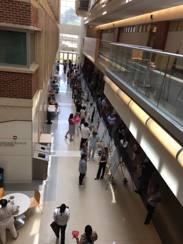 over looking summer intern poster session many are undergrads long hall way with many posters