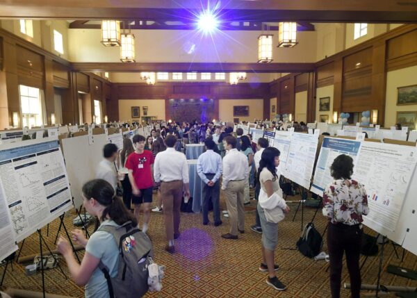 alumni center large room with many posters and students presenting and viewing research posters