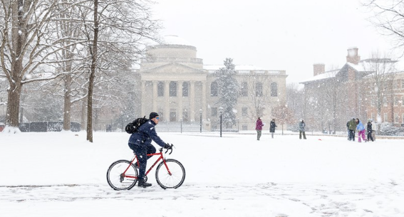 snow covered campus at UNC with a bicycle and 5 students standing in the snow
