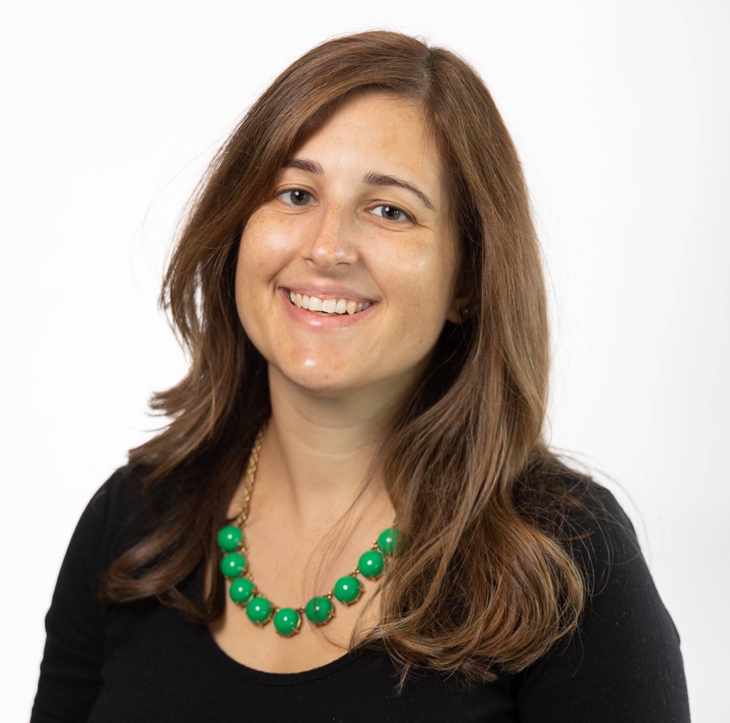 Dr. Emily Ciccone smiling in a black suit with green necklace