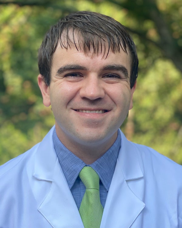 Photograph of Ben Albright, a smiling man in a white lab coat