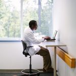 doctor at a table typing
