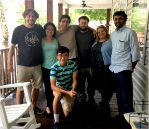 Seven members of the Hirsch lab poses on a porch with a rocking chair