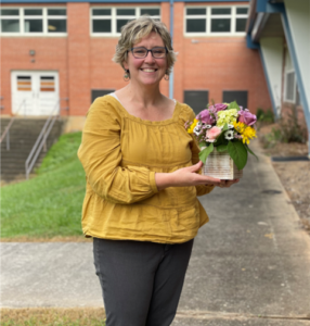 April Wilson holding flowers outside of school building