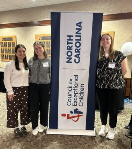 Three scholars standing with a poster for the North Carolina EC Conference