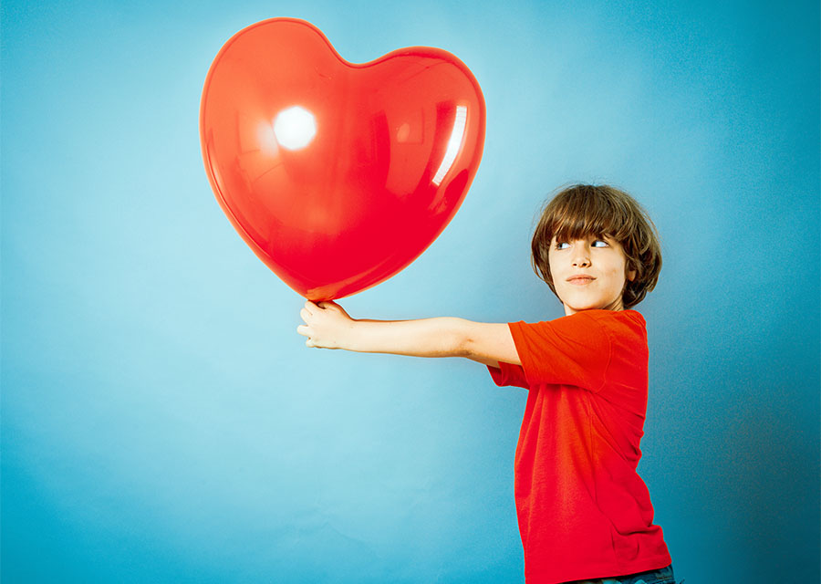 Boy holding a large heart-shaped balloon. Links to website where you can donate to the UNC HHT Center. 
