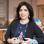Ronit Freeman in her lab at UNC campus holding plastic models of microscopic biomaterials
