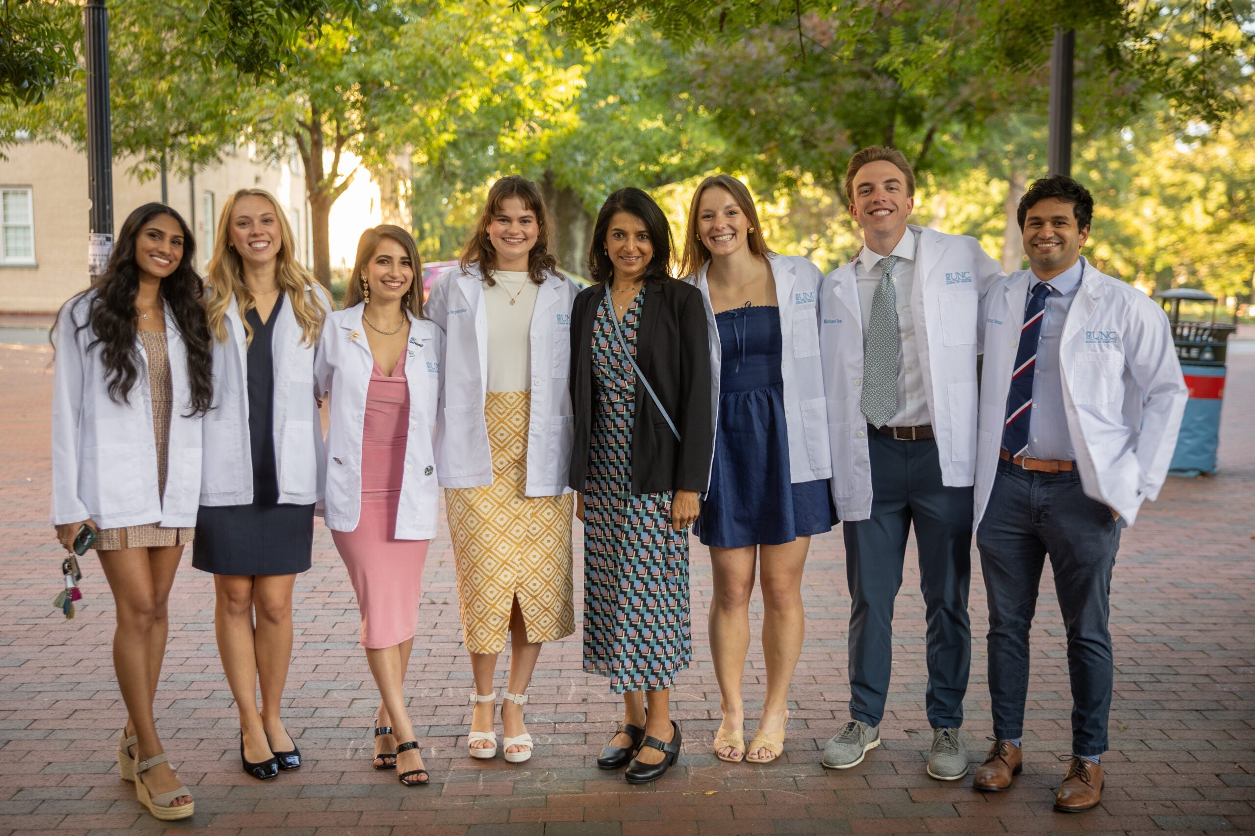 Students posing with their white coats outside Memorial Hall.