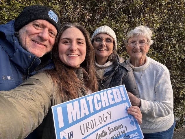 Katherine Poulos holding a Match Day sign with her family.