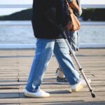old person walking with a cane on a boardwalk