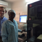 Jonathan Parr, MD, MPH, stands with a technician in front of the Abbott m2000 platform used to diagnosis hepatitis C virus.
