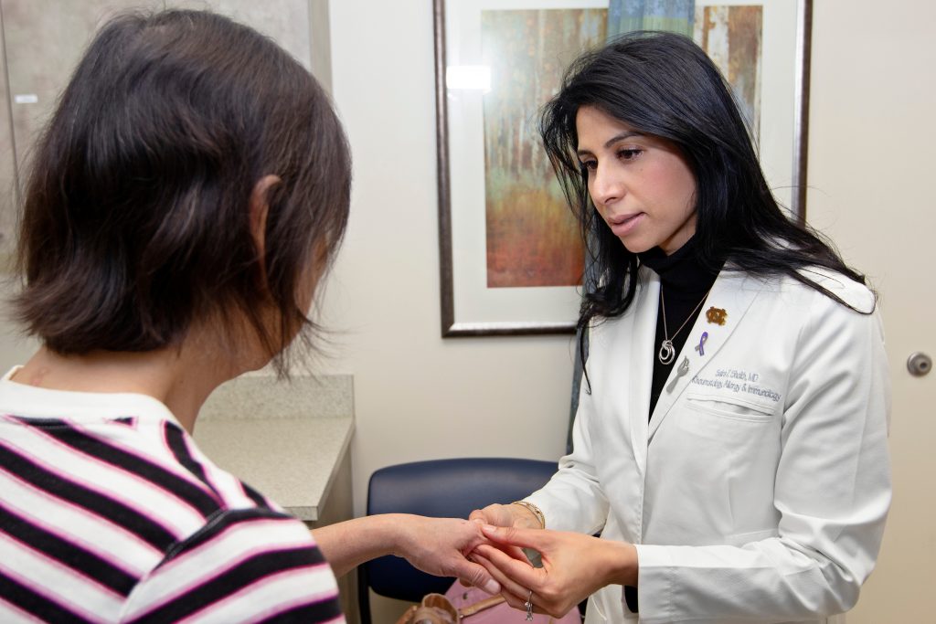 a physician evaluates a patient's hand joints in a medical office