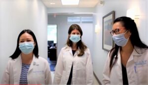 three physicians walk down a hallway with protective face masks on