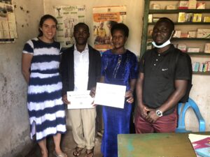 Uganda-malaria-Shelus-with-two-vendors-holding-training-certifications-Ross-Boyce-mentee