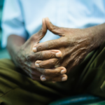 a man's geriatric hands, folder in his lap