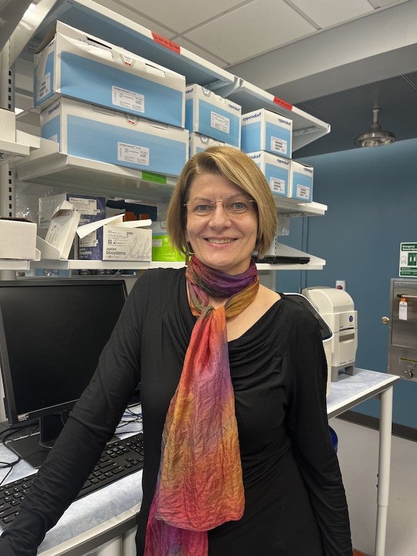 Woman with short hair, black shirt, multicolored scarf, glasses