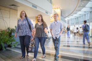 Mother with her teenage daughter and son walking through the lobby of the UNC Children's hospital
