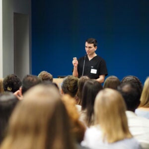 Dr. Faris Almubaslat presents at a podium to a full audience during a Neurology Day 2026 lecture.