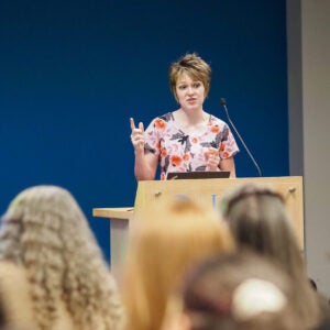 Dr. Krysten Lambeth presents at a podium to a seated audience during a Neurology Day 2026 lecture.