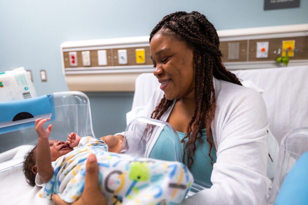 A mother with her newborn using the Couplet Care Bassinet created by UNC Researchers.