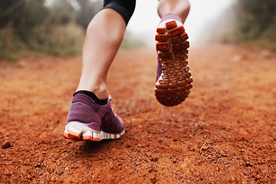 Closeup shot of a woman running on a trail on a misty morning