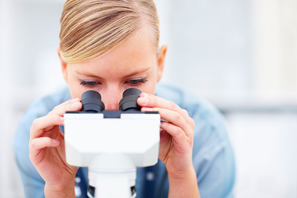 researcher looking through a microscope.