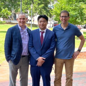 Dr. Matthew Cummins stands with his PhD advisors, Dr. John Sondek (left) and Dr. Brian Kuhlman (right) on the patio in front of the Genetic Medicine Building on UNC Campus after defending his PhD.