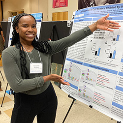 UNC Carolina Summer Fellowship student shows off their research poster