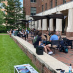 PharmFest 2022 attendees sit at tables on the Genetic Medicine Bldg. patio