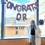 Dr. Amanda Graboski celebrates successfully defending her PhD thesis in front of large inflated balloons in the shapes of letters saying, "CONGRATS DR".