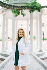 Amanda Graboski in her Pharmacology White Coat in front of the Old Well on UNC Campus