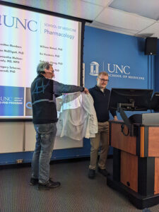 Dr. Gavin Schmitz receiving his Pharmacology white coat from co-PI, Bryan Roth, MD PhD, after he successfully defending his PhD.
