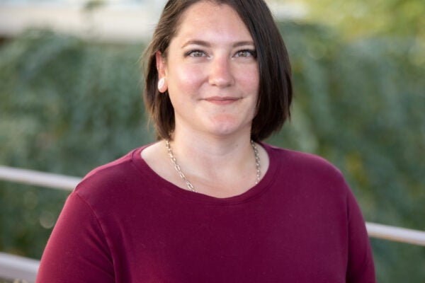 Brit Kim Headshot. Female with short brown hair and hazel eyes looking at the camera. She is wearing a long-sleeve maroon shirt.
