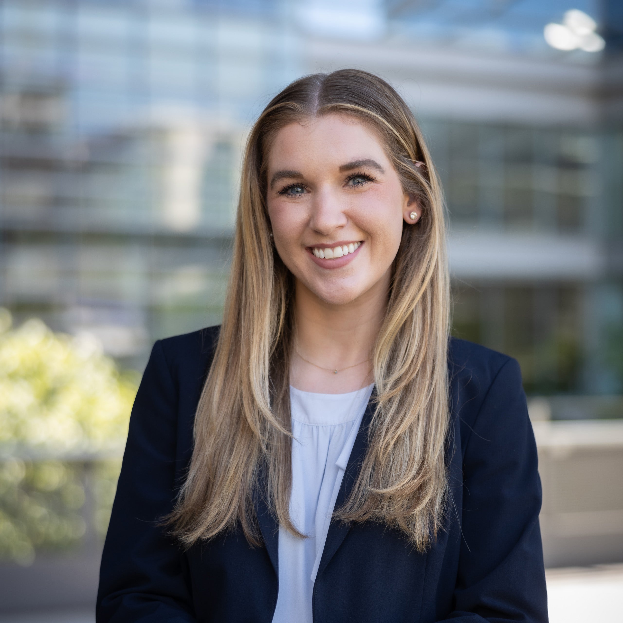 Ellen Jones's headshot. A female with long blonde hair and green eyes is smiling at the camera. She is wearing a white blouse and a navy jacket.