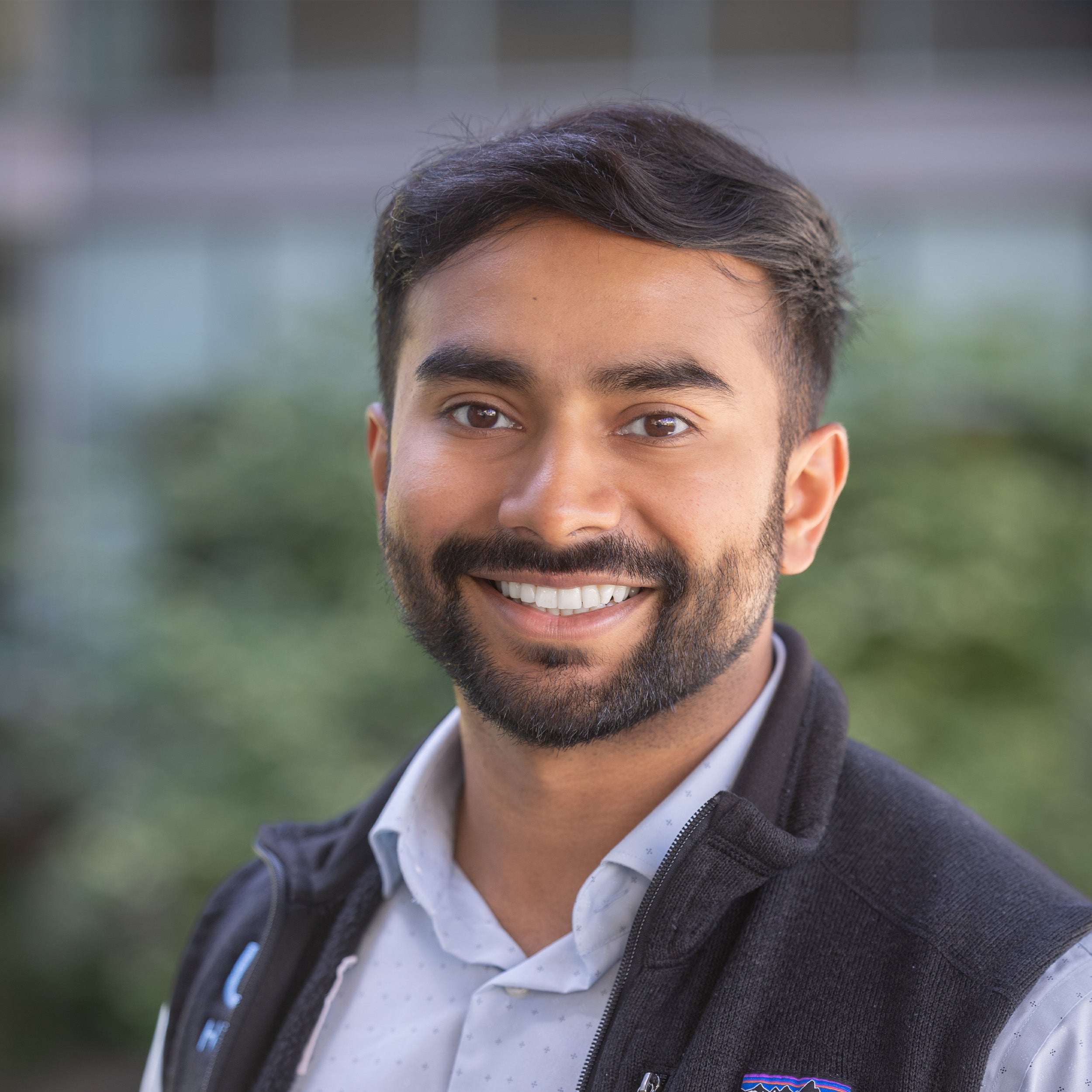 Naishal Patel, MD, headshot. Young Indian male with brown hair, brown eyes and beard smiling at the camera.