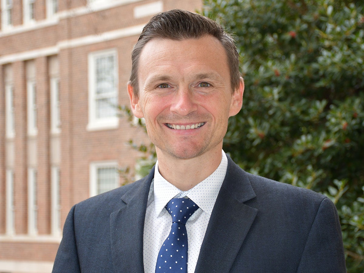 Professional head shot, outdoor background, office attire.