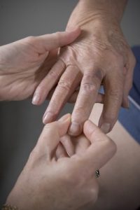 Provider examining hand of patient for osteoarthritis.